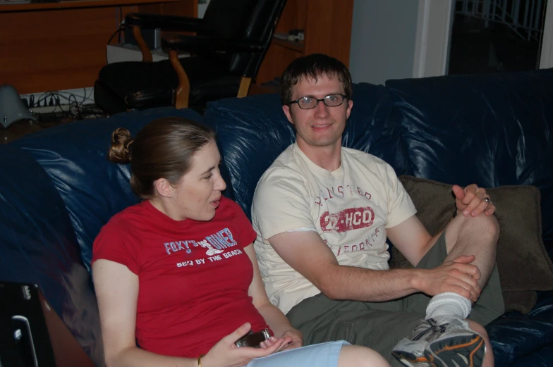 man sitting on couch with a woman sitting on a bed in front of him