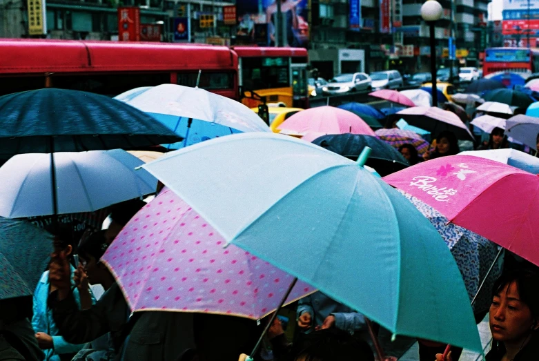 several people holding umbrellas in a busy city street