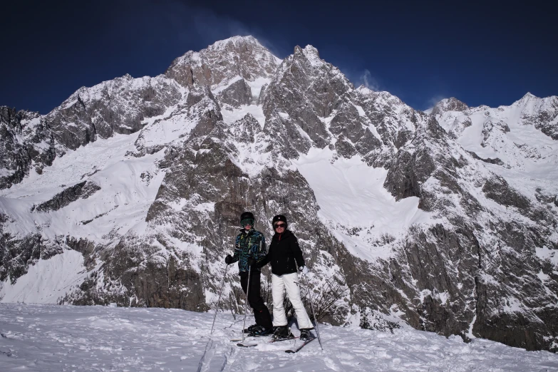 three people standing on top of a snowy mountain