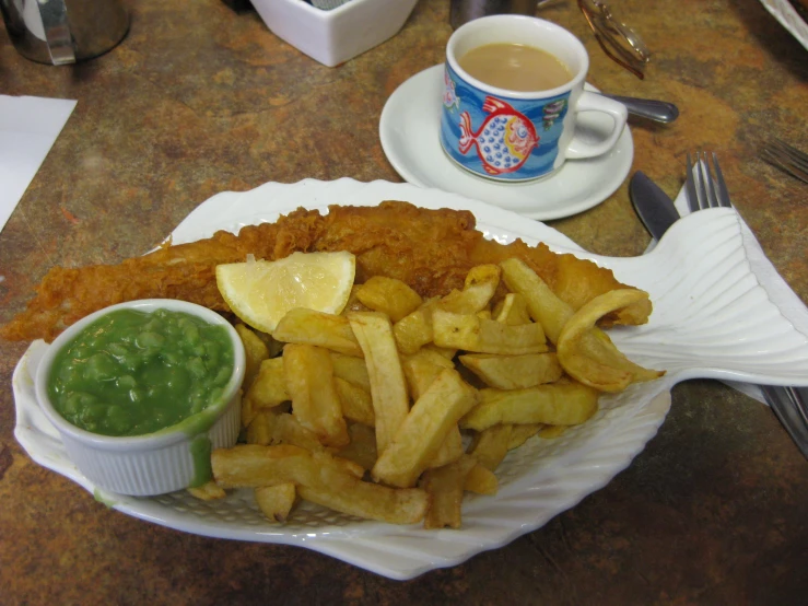 fish and chips, french fries, and a cup of tea are on the table