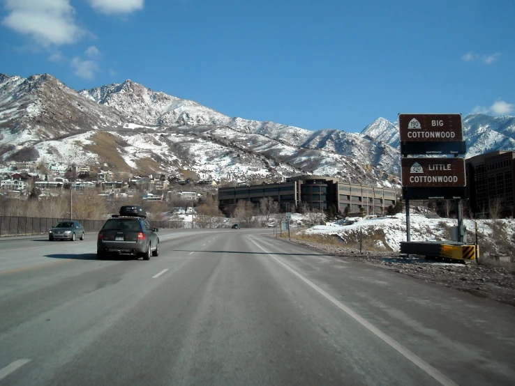 a road near snow capped mountains and a building