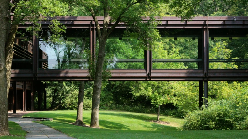 a brown train traveling over a bridge next to a green forest