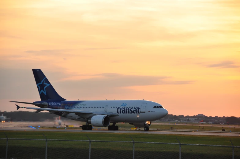 an airplane that is on the tarmac at sunset