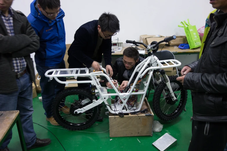 three people work on a bike in a shop