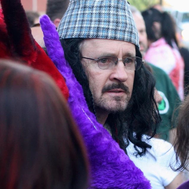 a man in plaid hat sitting on purple stuffed animal