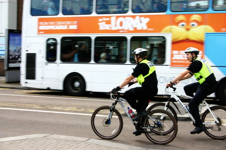 two men riding bicycles in front of a bus