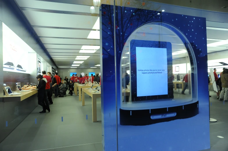 people are walking past a television and cellphone shop