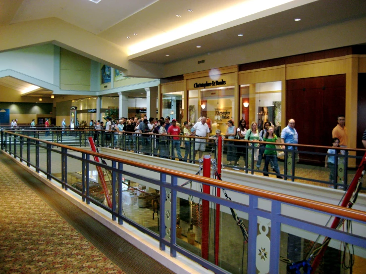 people stand in line on an escalator inside a mall