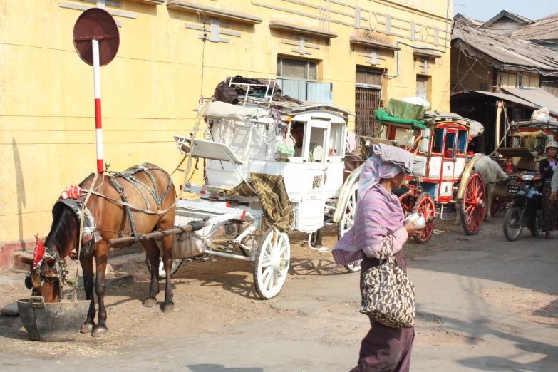 people are walking near two horse drawn carriages