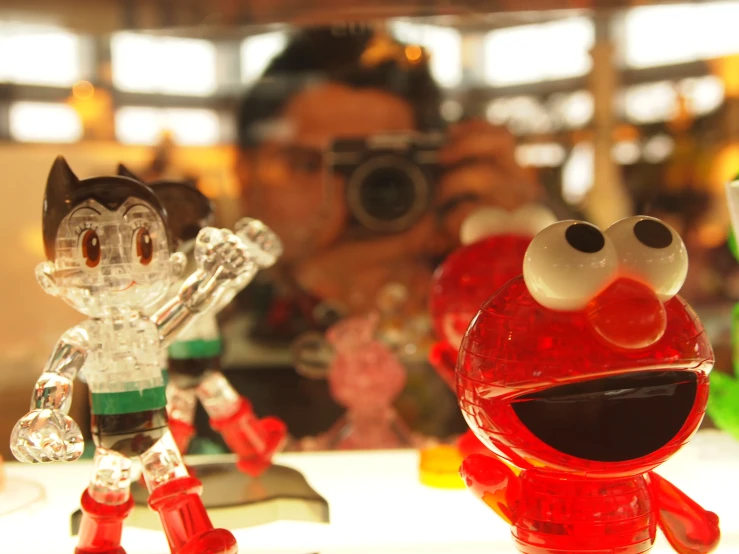 a camera man taking pictures at the counter with glass figurines in front of him