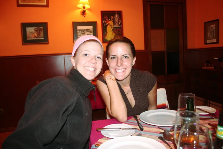 two woman are smiling and sitting at a table