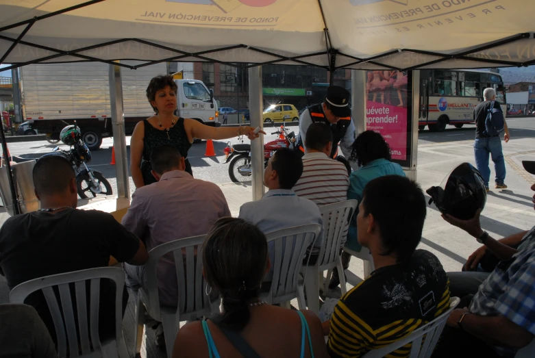 a group of people seated around each other on chairs under a gazebo