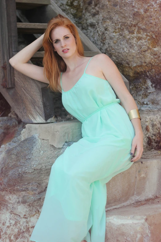 a woman wearing a green dress sitting on some steps