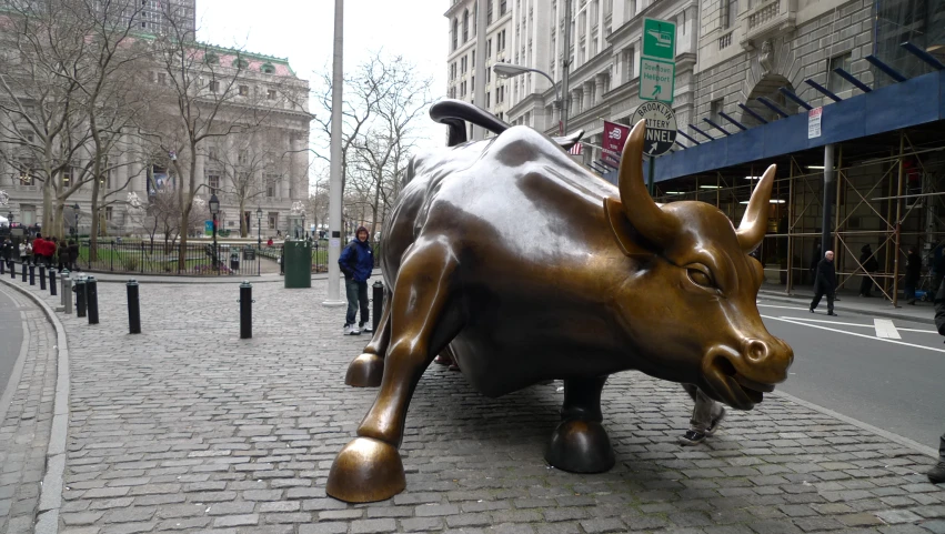 bronze statue of bull in the middle of a city street