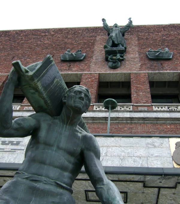 a statue of a man holding a box in front of a brick building