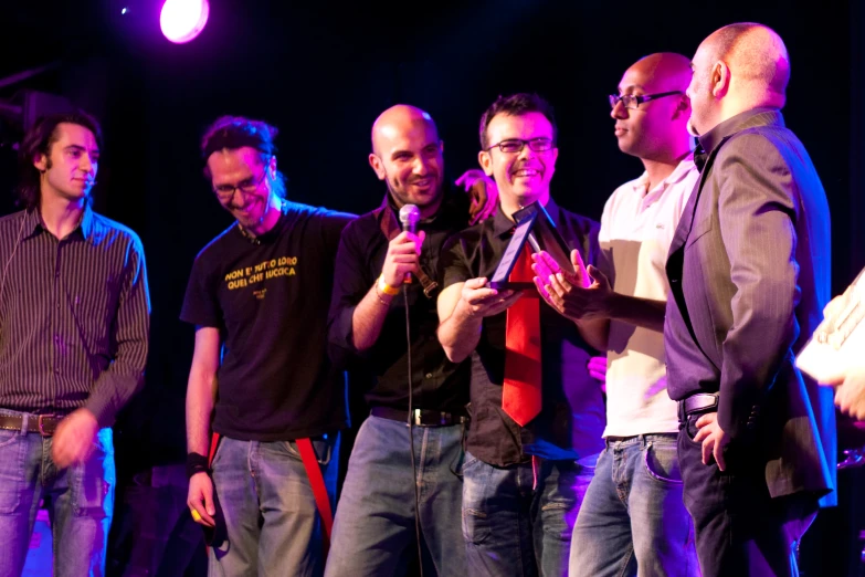 five men standing on a stage with microphones