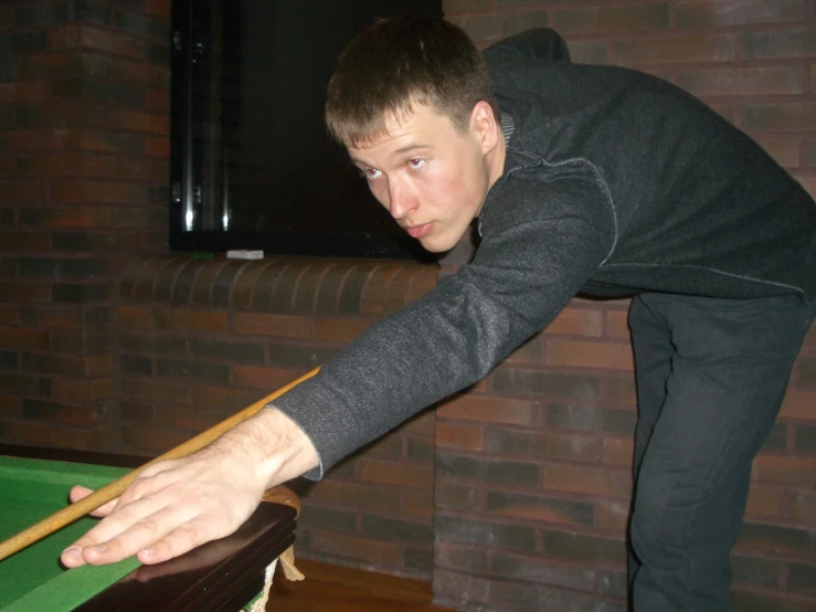 a man leaning over a green pool table