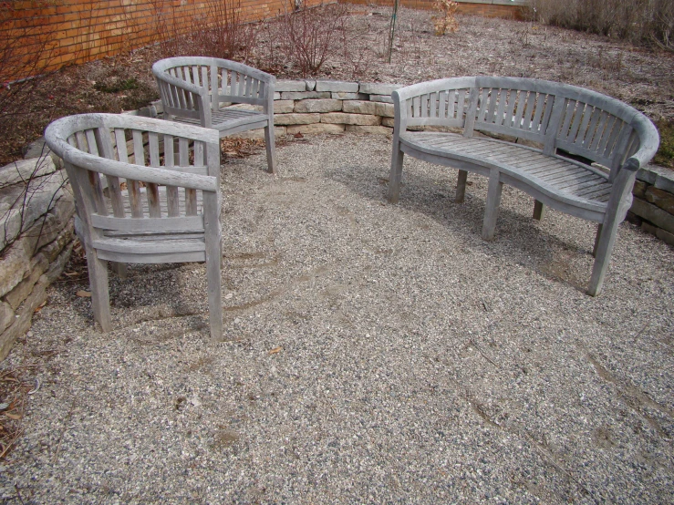 three wooden benches with brick wall in the background