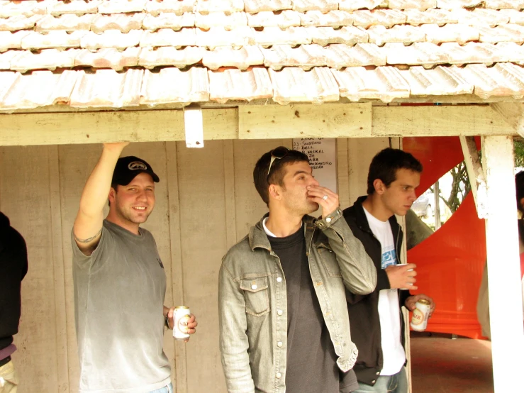 the men are standing outside together while drinking