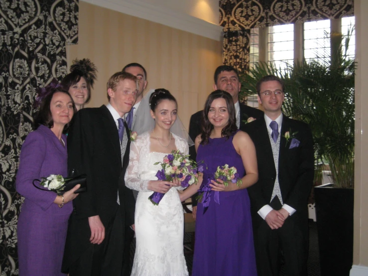 the bride and grooms pose with their family before the wedding
