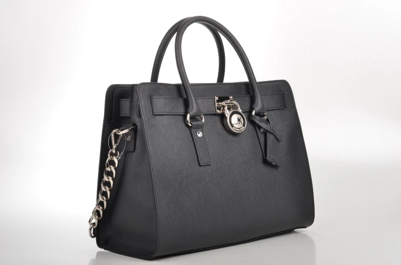 a black tote bag with gold chains hanging from the handles