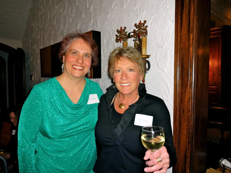 two women are posing for a picture while holding a glass of wine