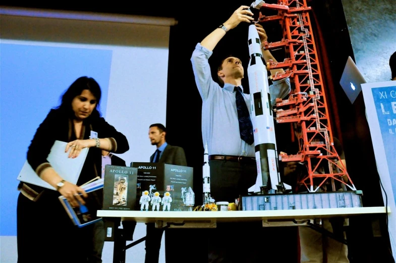 a man standing next to a woman holding up a small model