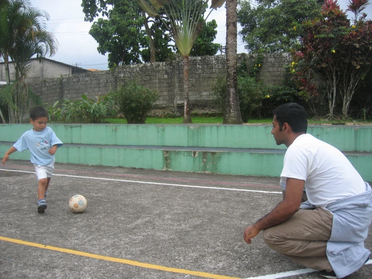 father and son playing with a soccer ball together
