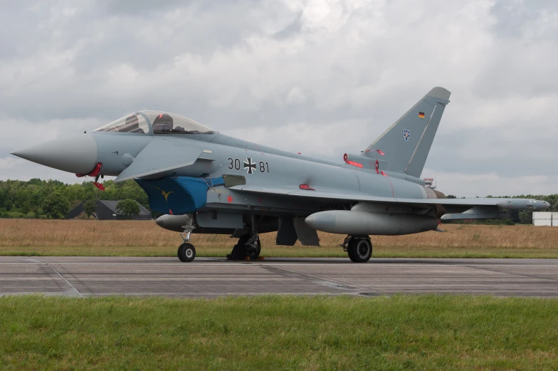 a fighter jet sits on a tarmac during an airfield