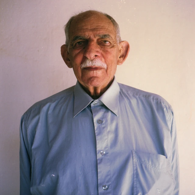 an older gentleman wearing a dress shirt and tie