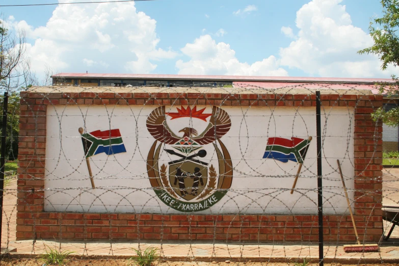 a flag and two flags on a fence next to a sign