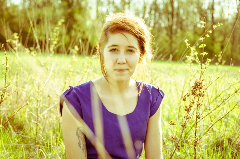 a beautiful young woman posing in a green field