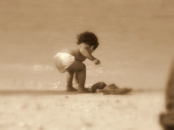 a little boy playing with some sand on the beach