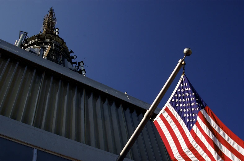 the american flag is flying in the wind beside a building