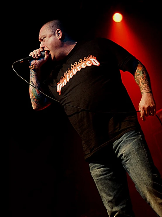 a bald man singing into a microphone while performing