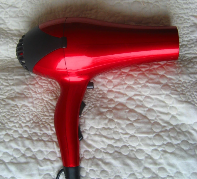 a red hair dryer is laying on a bed