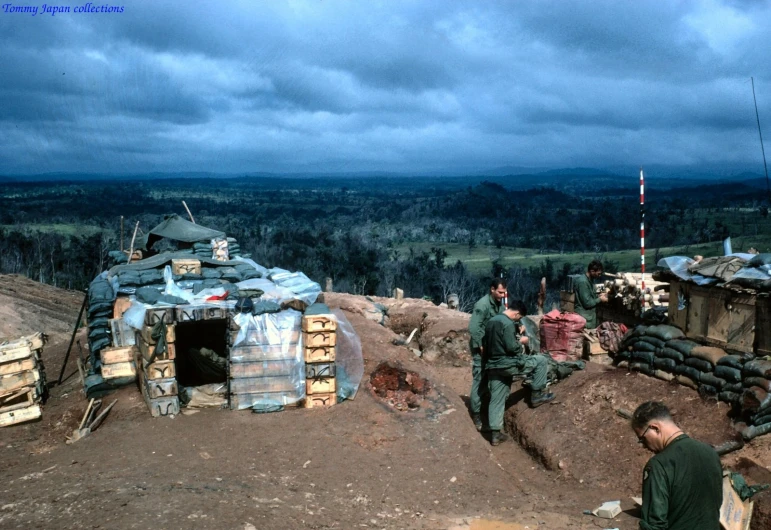 people stand around a pile of bricks in the field