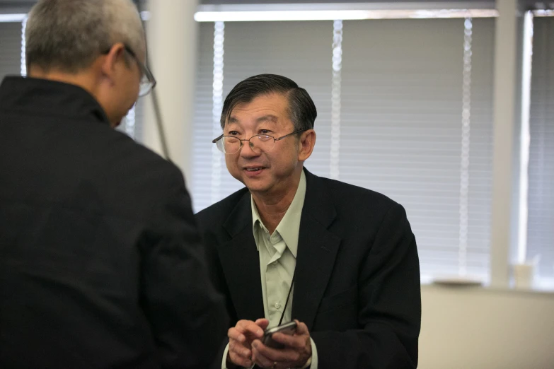 a man talking to another man sitting in a chair