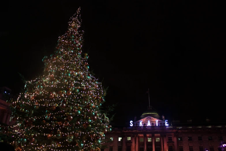 a lighted christmas tree sits in front of the capitol building