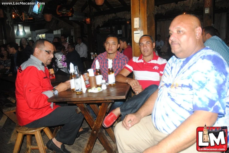 people sitting at wooden tables drinking beer at a bar