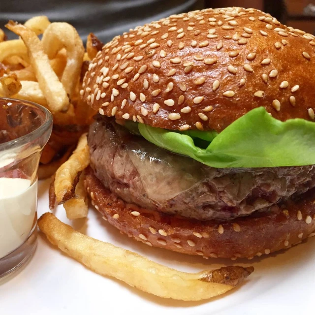 a big hamburger on a bun with cheese fries