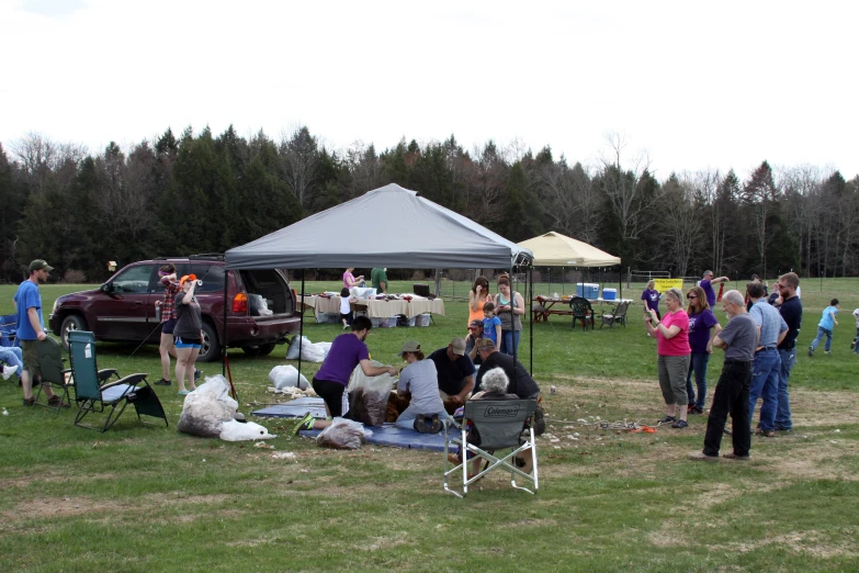 people are gathered around a small tent to eat