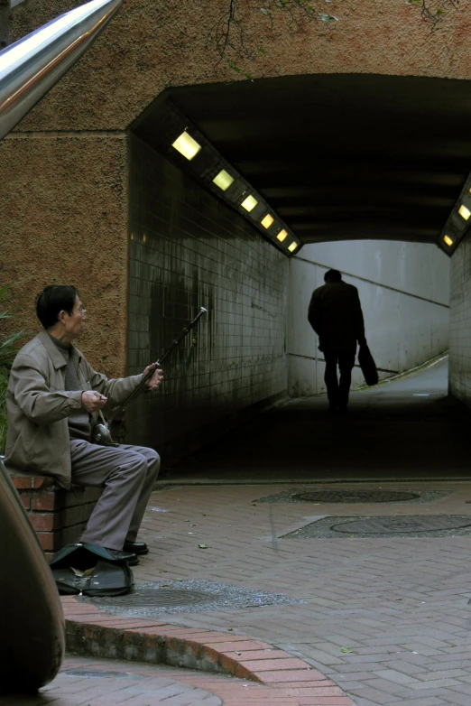 a man sitting on a bench while looking into the dark tunnel