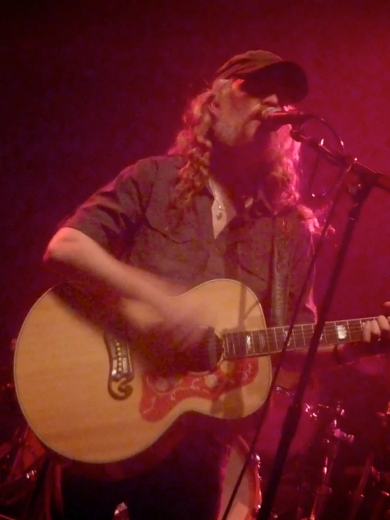 a man singing into a microphone with a guitar