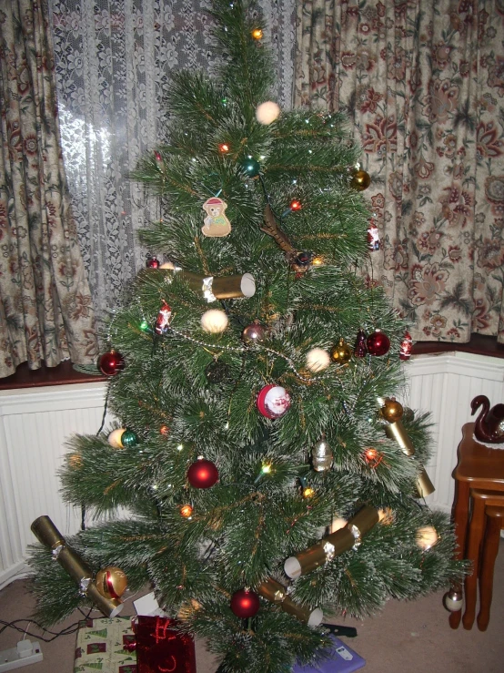 christmas tree with gifts under lit christmas decorations