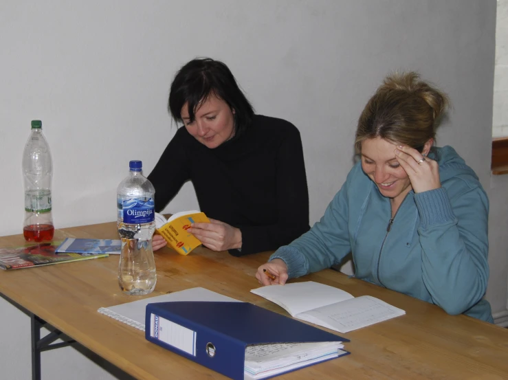 a lady sitting at the desk and another woman holding a book