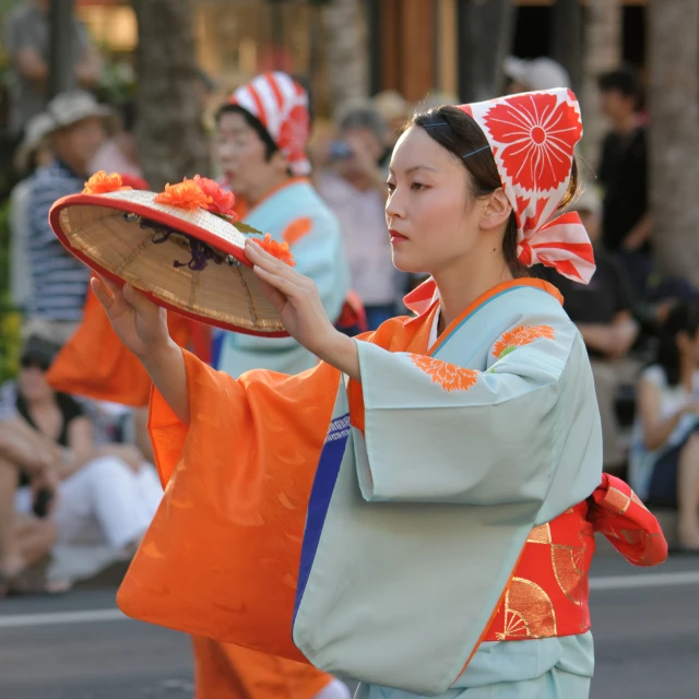 a woman with her hair tied back and wearing an orange oriental hat