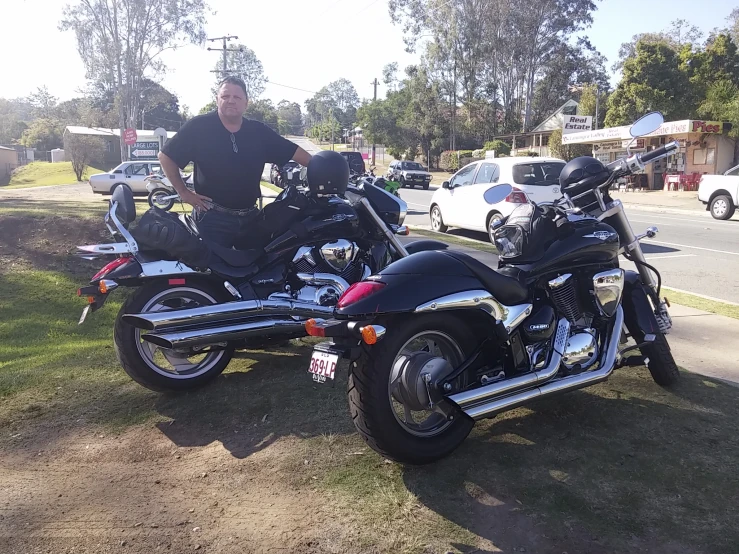 two motorcycles are parked on the grass near a street