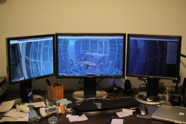 three monitors on a desk next to each other