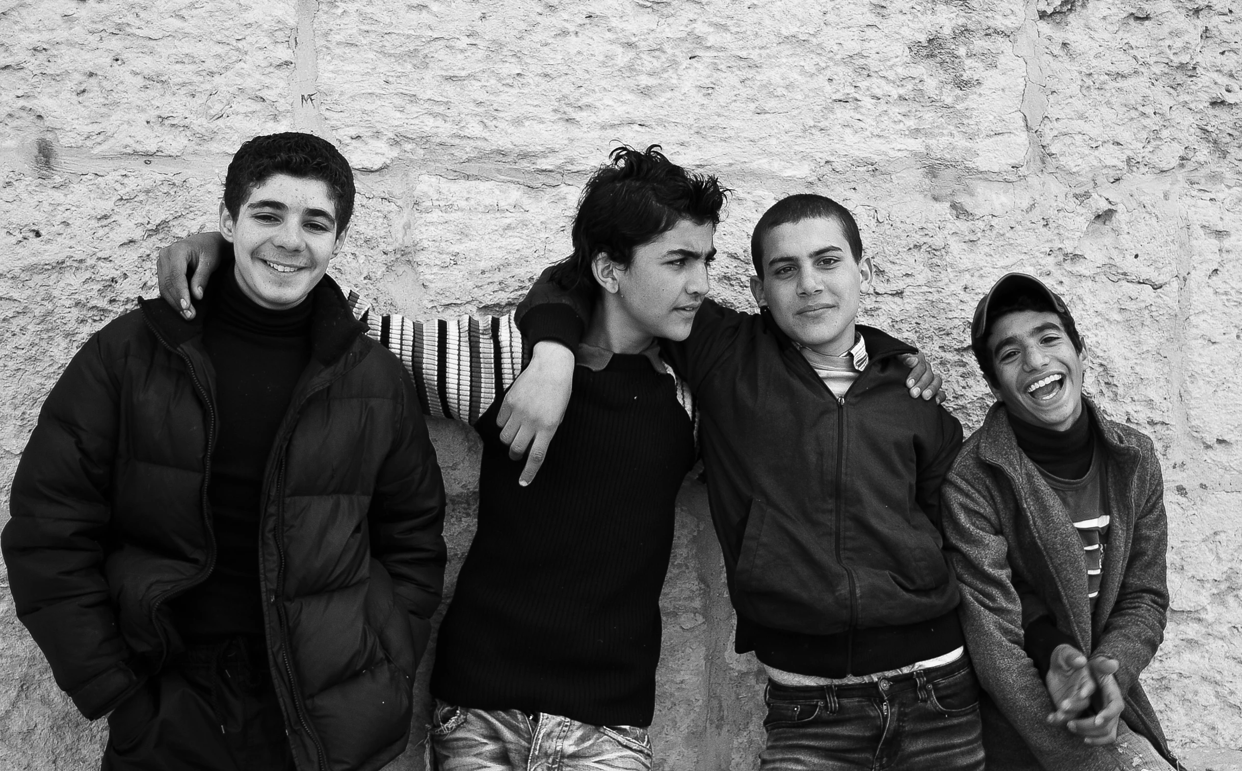 four young men standing together in front of a wall